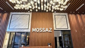 A reception area with a wooden desk and a marble wall. - Mossaz Suites by Mykey Global (Kuala Lumpur)