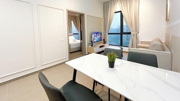A modern living room with a dining area, a sofa set, a TV, and a view of the sea. - Mossaz Suites by Mykey Global (Kuala Lumpur)