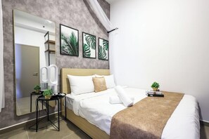 Habitación de hotel con un espejo grande, una cama con ropa blanca, un plaid marrón y una pequeña mesa con una planta.
