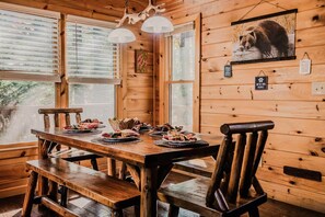 A wooden interior with a dining table set for four, surrounded by wooden chairs. - Owls and Friends - 3 King Bedroom with ensuites-Hot tub-Pool Table (Blue Ridge)