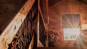 A wooden interior with a sloped ceiling, a window with a view of sunflowers, and a lamp. - Owls and Friends - 3 King Bedroom with ensuites-Hot tub-Pool Table (Blue Ridge)