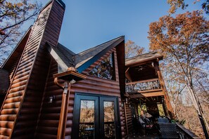 Eine Blockhütte mit einem markanten Schornstein, einem Balkon und einer Tür mit Glasfeldern.