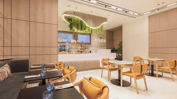 Ein modernes Restaurant mit Holzwandverkleidung, einer zentralen Theke mit Speisekarte und Sitzbereichen mit Tischen und Stühlen.