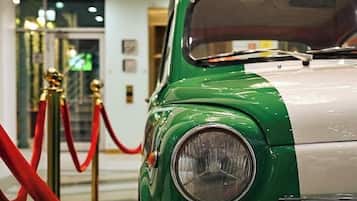 Un coche antiguo con una combinación de colores verde y blanco, estacionado en el interior con una barrera de cuerda roja.
