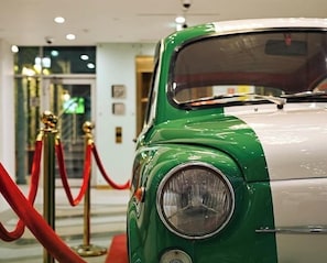 A vintage car with a green and white color scheme, parked indoors with a red rope barrier. - Central Inn Hotel & Suites Al Sadd (Doha)