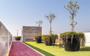 A rooftop terrace with artificial grass, potted plants, and seating areas. - Central Inn Hotel & Suites Al Sadd (Doha)