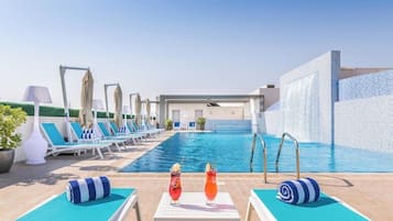 Zona de piscina con sillones reclinables, piscina y barra con bebidas.
