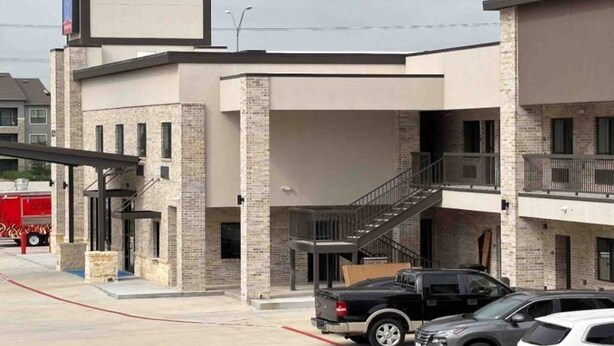 A multi-story building with a brick facade, a covered entrance, and a staircase leading to an upper level. - Studio6 Humble, TX (Humble)