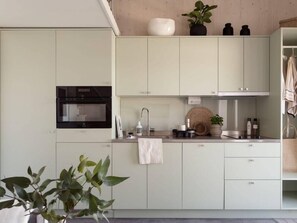 Una cocina moderna con horno empotrado, un lavamanos y armarios.