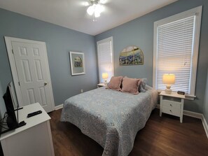 A bedroom with a bed, bedside tables, a lamp, a painting, and a door. - Center of the action - Family and Pet Friendly (Apex)