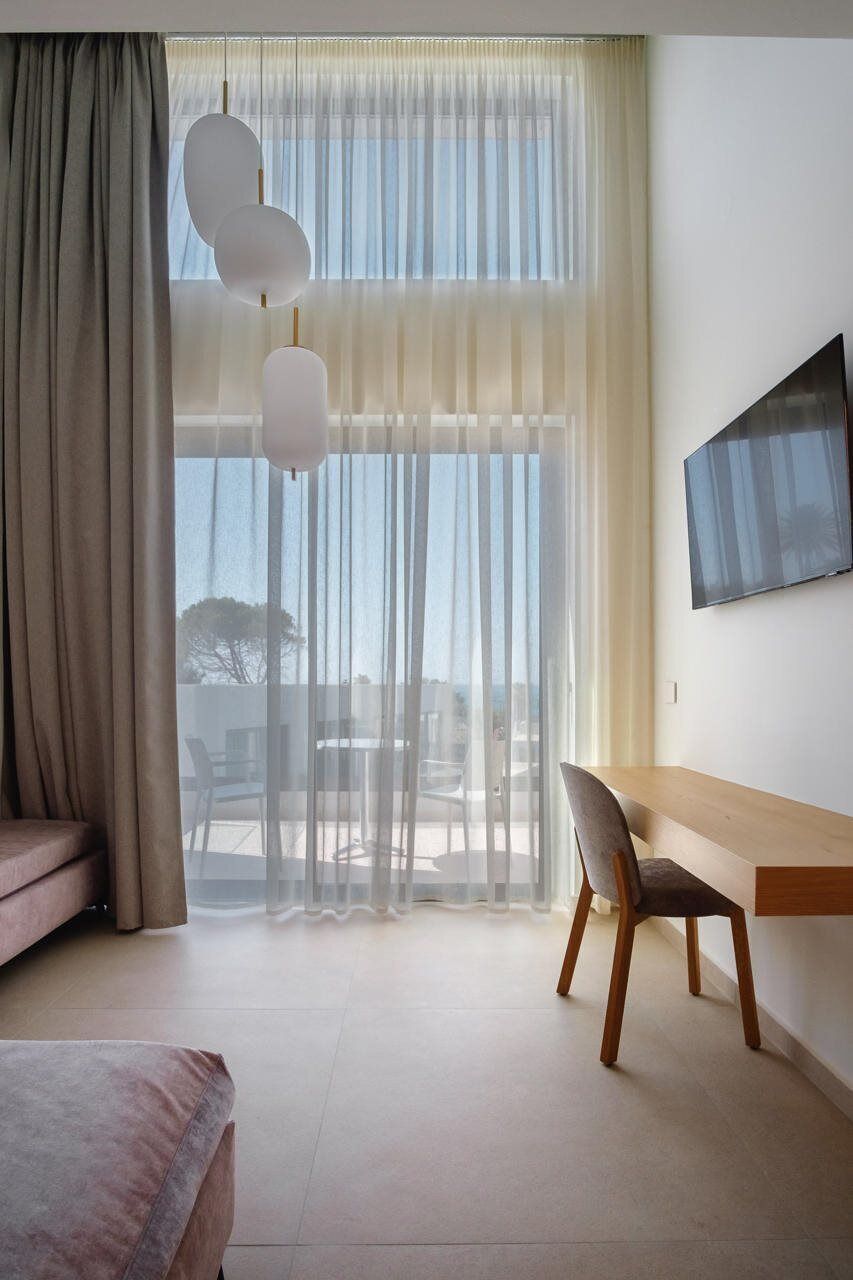 Een moderne kamer met een groot raam, een bed, een bureau en een stoel.
