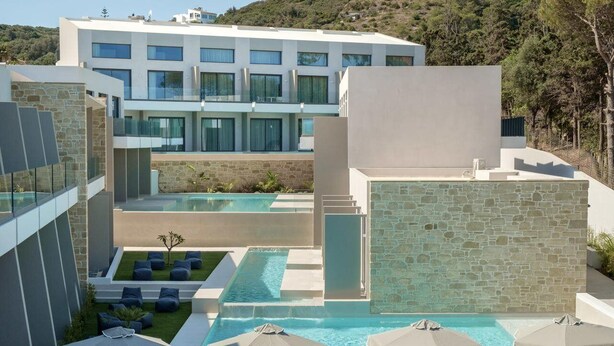 A modern hotel with a pool area, outdoor seating, and a view of the surrounding landscape. - Phos Hotel - Adults Only (Chania)