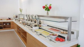 A buffet setup with various food items and a glass display case. - Phos Hotel - Adults Only (Chania)