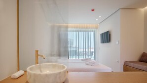 A modern bathroom with a large white basin, a gold faucet, and a wooden countertop. - Phos Hotel - Adults Only (Chania)