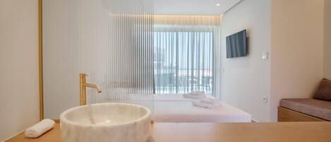 A modern bathroom with a large white basin, a gold faucet, and a wooden countertop.
