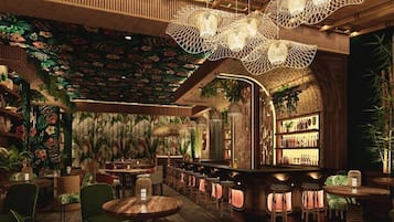 A bar area with wooden furniture, hanging lights, and a tropical-themed wall.