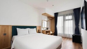 A hotel room with a large bed, a wooden headboard, a desk with a chair, and a large window with curtains. - Haven Hut Riverside (Ho Chi Minh City)