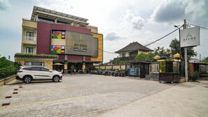 A hotel with a large sign, a parking area, and a building with a traditional roof.