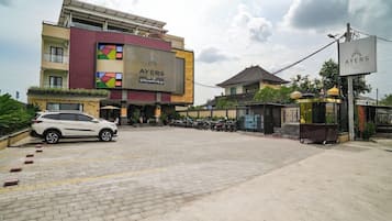 A hotel with a large sign, a parking area, and a building with a traditional roof.