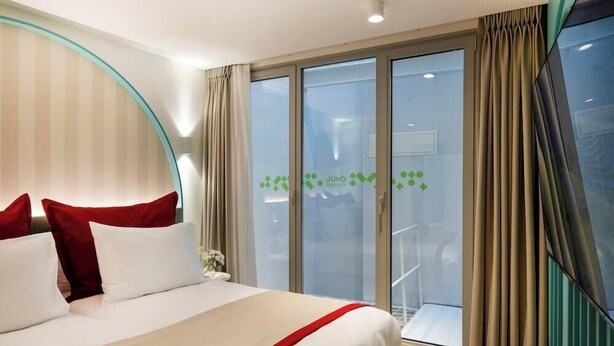 A hotel room with a bed, curtains, and a view through a glass door. - Juno Residences (Istanbul)