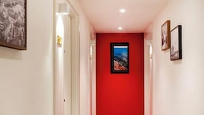 A hallway with a red carpet, white walls, and a framed picture on the right. - Juno Residences (Istanbul)