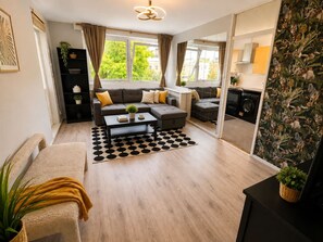 A modern living room with a sofa, coffee table, and a view of the city. - 1 Bdr Sleeps 4 1 Bath Holland Park (London)