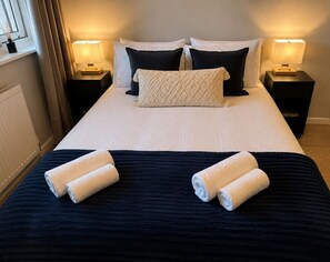 A hotel room with a neatly made bed, two bedside lamps, and a window with curtains. - 1 Bdr Sleeps 4 1 Bath Holland Park (London)