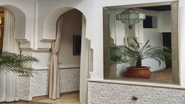 A hallway with white walls, a large mirror, and a potted plant. - Riad El Khaeir Hammam & Spa (Marrakech)
