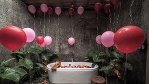 Ein Wellnessbereich mit Badewanne, umgeben von Pflanzen und Ballons.