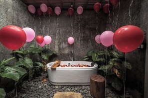 A spa area with a bathtub, surrounded by plants and balloons.