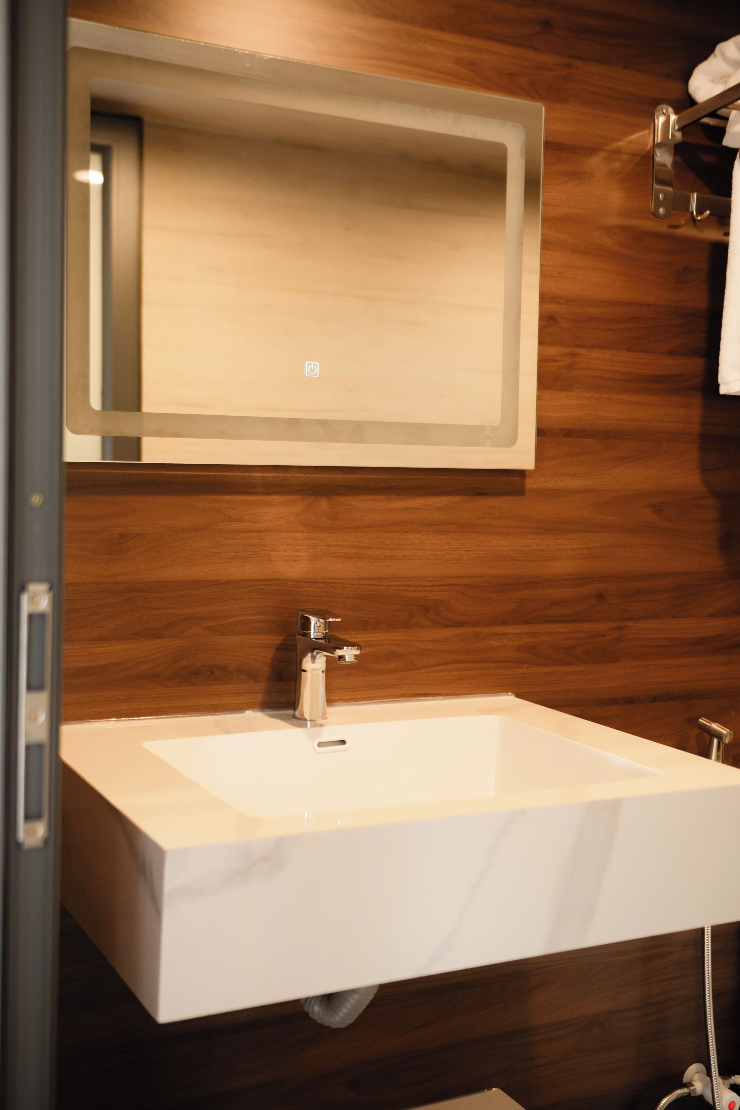 A bathroom with a white sink, a mirror, and wooden wall paneling.