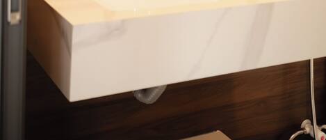 A bathroom with a white sink, a mirror, and wooden wall paneling.