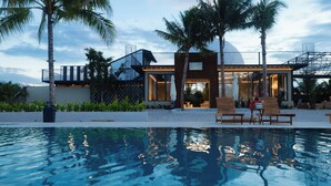 Un hôtel moderne doté d’une piscine, de palmiers et offrant une vue sur un ciel dégagé.