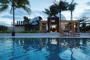 Un hotel moderno con piscina, palmeras y cielo despejado.