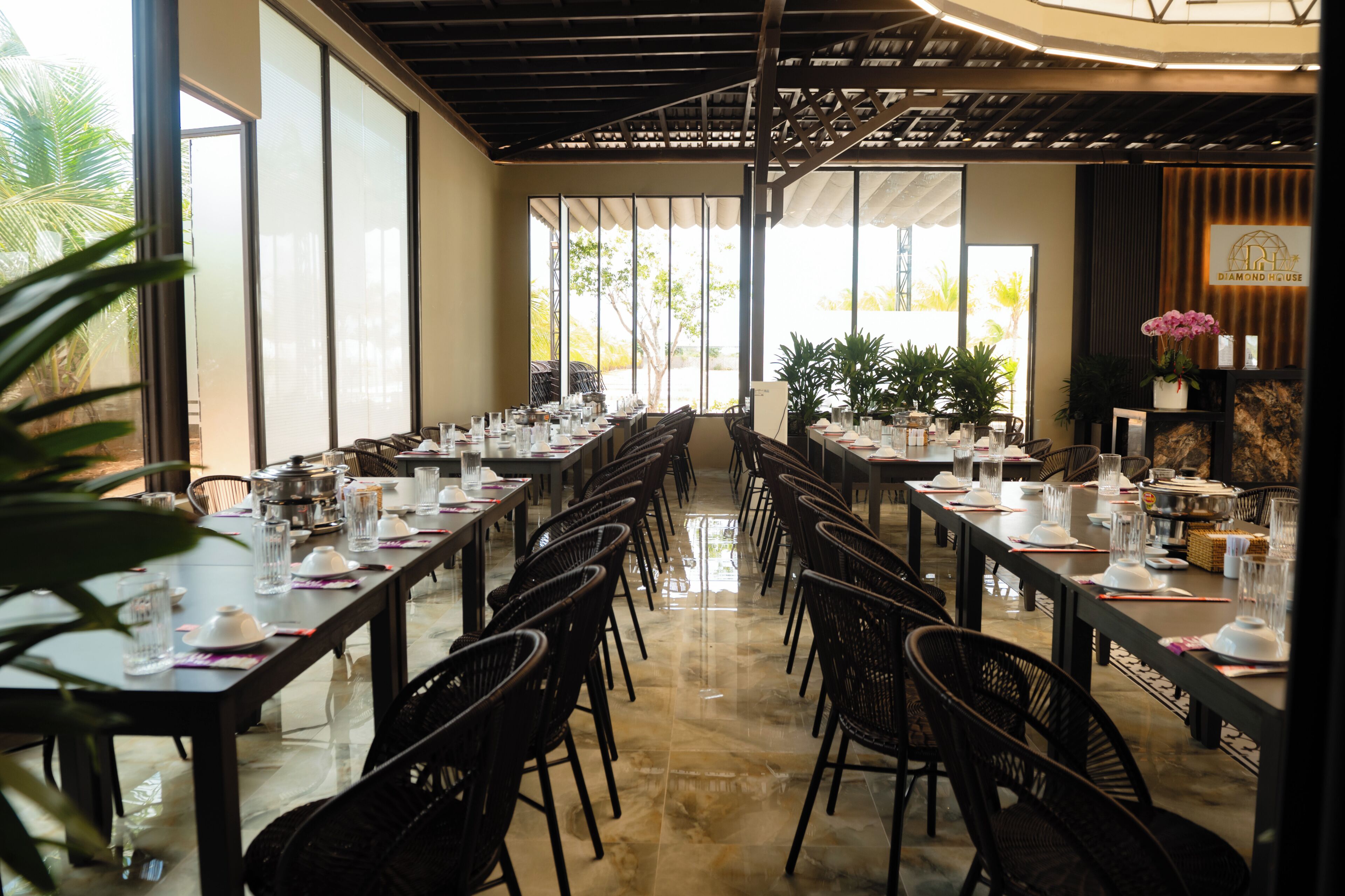 Un grand espace dédié à la salle à manger, avec de longues tables, des chaises et une vue sur l’extérieur.