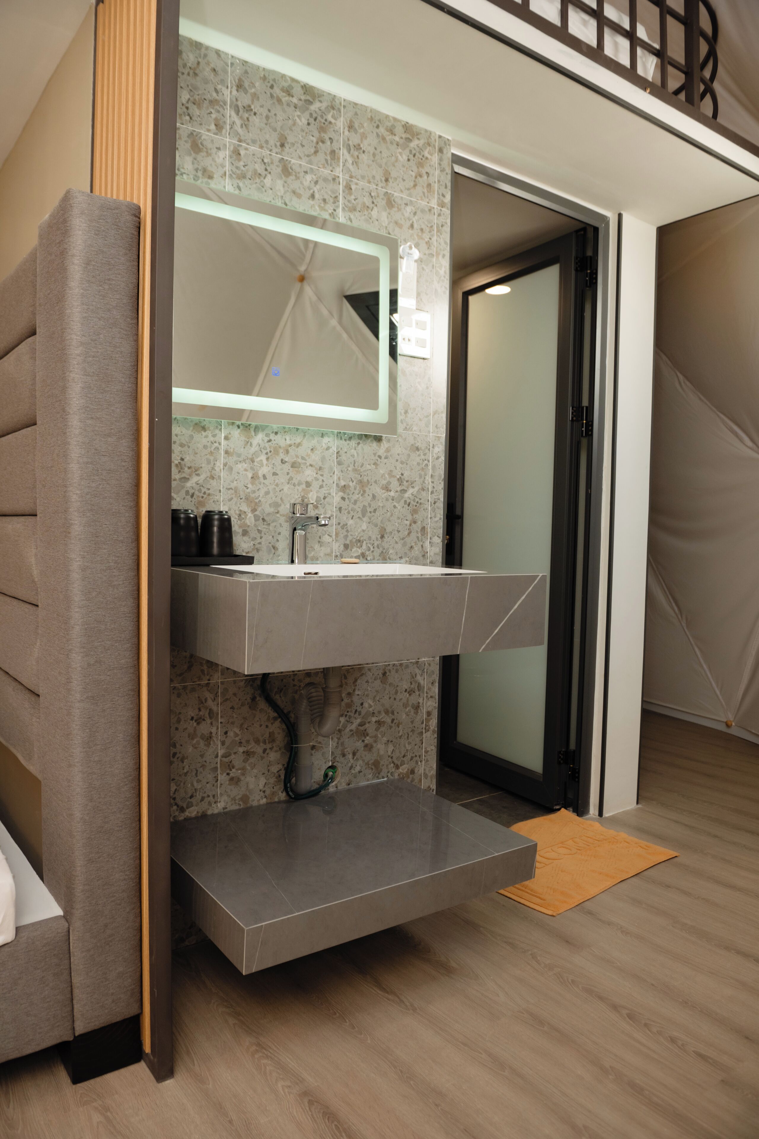 A modern bathroom with a built-in sink, a mirror, and a shower area.