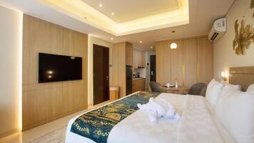 Une chambre d’hôtel avec un lit, un téléviseur à écran plat, un coin repas et une cuisine en arrière-plan.