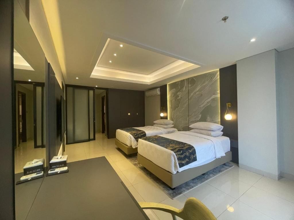 Una habitación de hotel moderna con dos camas, un espejo grande y una zona de estar.