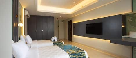 A modern hotel room with a large bed, a smaller bed, a flat-screen TV mounted on the wall, and a ceiling with recessed lighting.