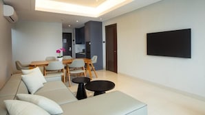 Un moderno salón con sofá, mesa de comedor y sillas. Hay un televisor de pantalla plana montado en la pared.