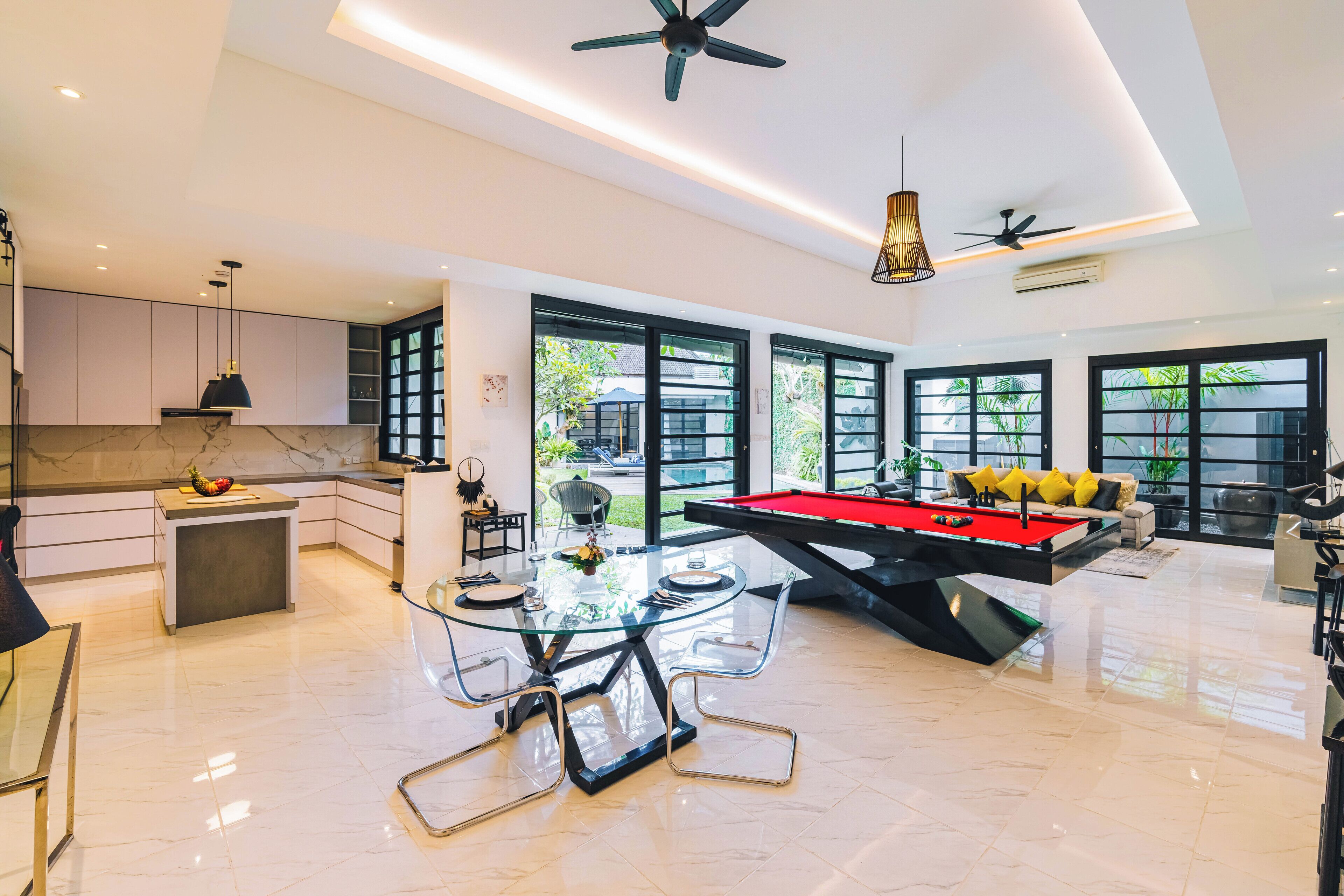 Amplia sala de estar con mesa de billar, comedor y cocina equipada con electrodomésticos modernos.