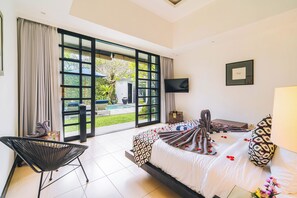 Ein Hotelzimmer mit Bett, einem Sessel, einem Fernseher und Blick auf einen Pool.