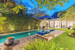 Uma piscina com espreguiçadeiras e um deck de madeira.