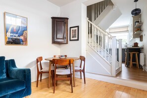 Un comedor con una mesa y sillas de madera, un sofá azul y una escalera que sube a un nivel superior.