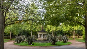 A park with a central fountain surrounded by manicured grass and trees. - Park Crescent Mews East II (London)