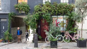 A building with a red door, a bicycle parked in front, and a sign with a crown symbol. - Park Crescent Mews East II (London)