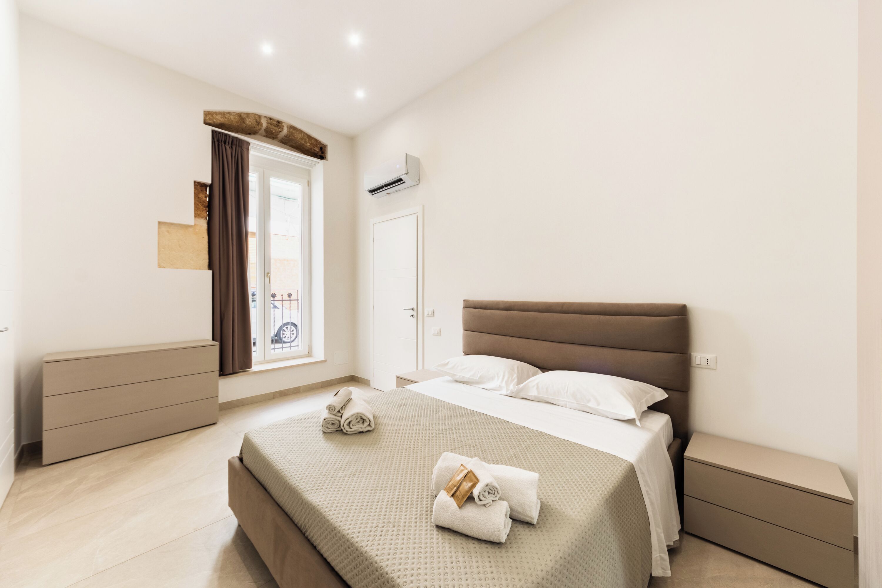 Un dormitorio moderno con una cama grande, un aparador, un armario y un equipo de aire acondicionado.