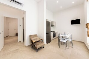 A modern kitchen with a built-in oven, a dining table with chairs, and a flat-screen TV mounted on the wall. - Incanto Holiday House - Appartamento 2 (Avola)