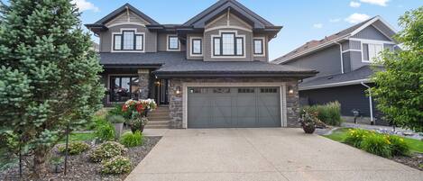 A two-story house with a stone facade, a garage, and a driveway.