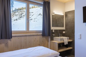 Ein modernes Badezimmer mit einem Holzbadschoenung, einem großen Spiegel und Blick auf einen verschneiten Berg.